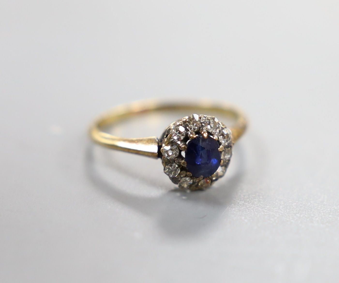 An early 20th century yellow metal, sapphire and diamond set oval cluster ring, size I/J, gross weight 1.7 grams.